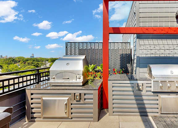 A modern outdoor kitchen with stainless steel appliances and a red frame.