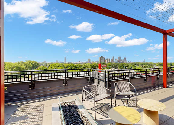 A red metal structure with a table and chairs in front of a city skyline.