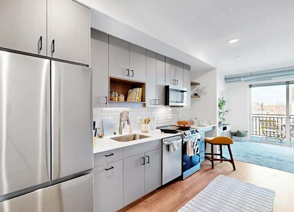 A modern kitchen with stainless steel appliances and a wooden floor.