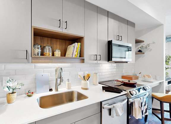 A modern kitchen with a white countertop and stainless steel appliances.