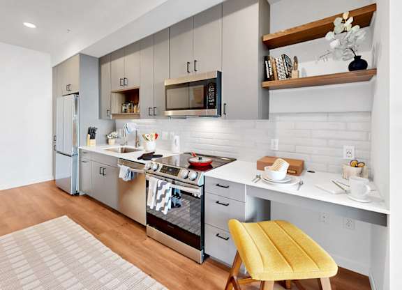A modern kitchen with a yellow chair and white cabinets.