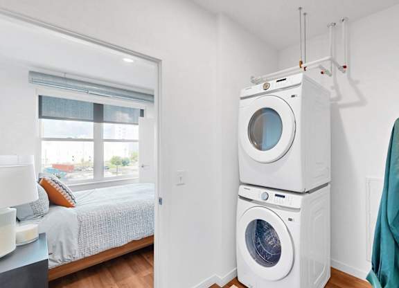 A white washer and dryer stacked on top of each other in a laundry room.