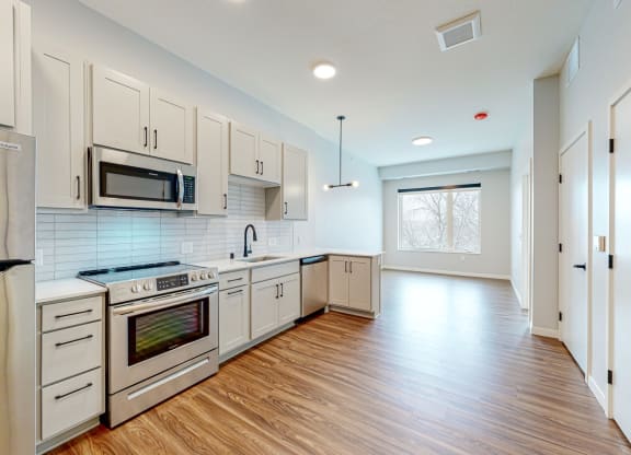 a kitchen with white cabinets and a wooden floor