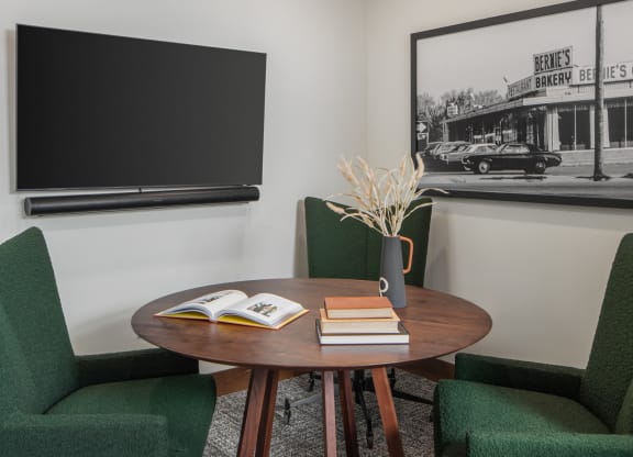 a room with a table with a book on top of it and three green chairs around it