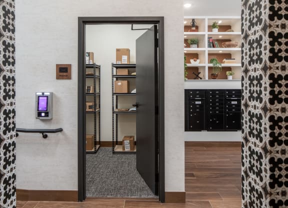 a corridor with a black door and a white wall with shelves in the background