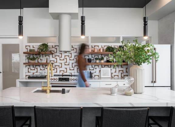 a kitchen with a white counter top and black chairs