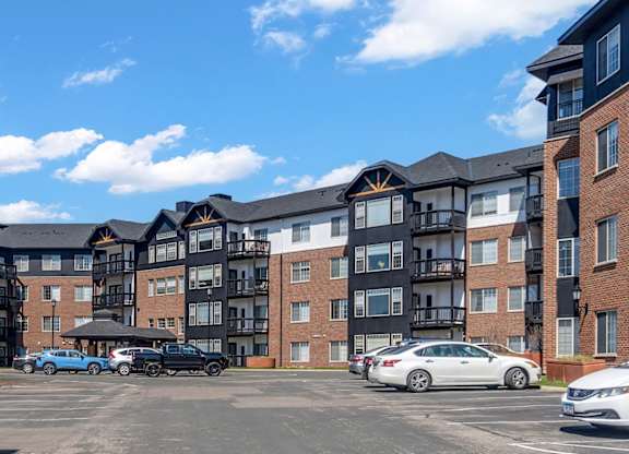 A parking lot in front of a large apartment complex.