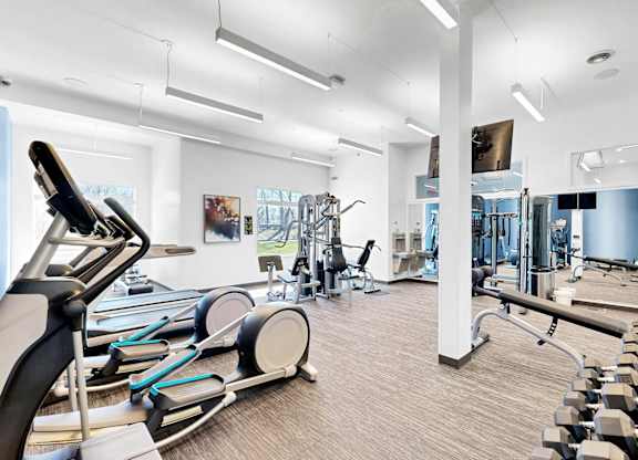 A gym with a variety of equipment including treadmills, weights, and exercise machines.