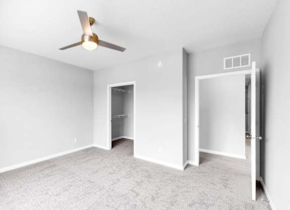 A room with a ceiling fan and carpeted floor.