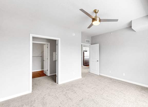 A room with a ceiling fan and carpeted floor.