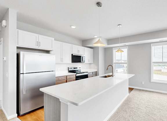 A modern kitchen with a white island and stainless steel appliances.