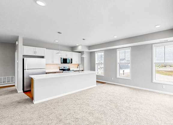 A spacious, empty room with a kitchen area and a window.