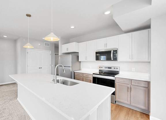 A modern kitchen with a white countertop and stainless steel appliances.
