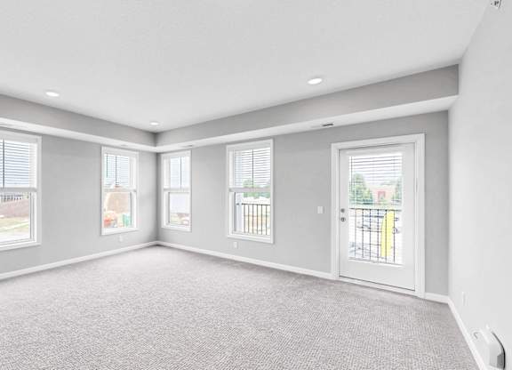 A spacious room with grey carpeting and white walls.