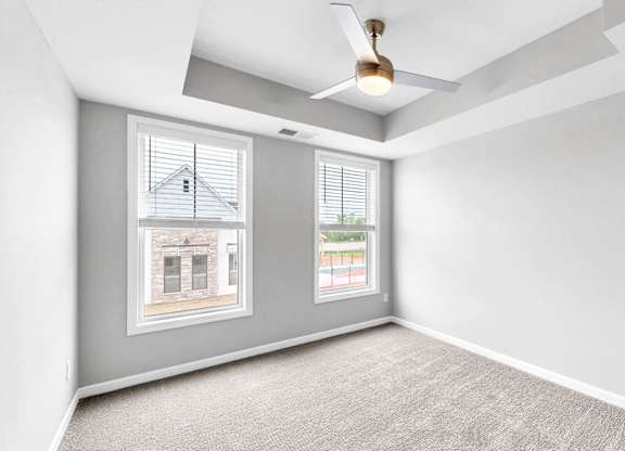 A room with a carpeted floor and a ceiling fan.