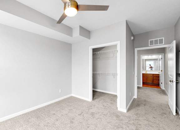 A room with a ceiling fan and carpeted floor.