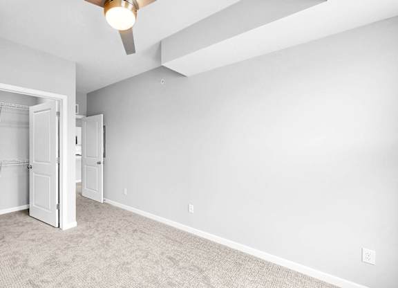A room with a ceiling fan and a doorway leading to another room.