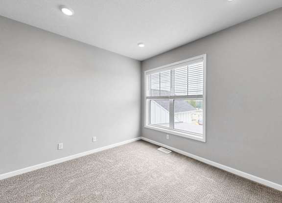 A room with a window and a carpeted floor.