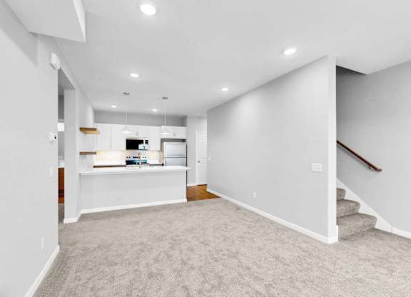 A spacious, empty room with a staircase on the right side.