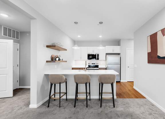 A kitchen with a bar stool and a painting on the wall.