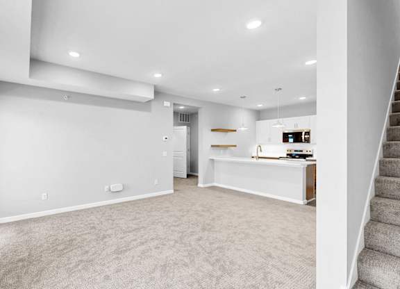 A spacious, empty room with a staircase on the right side.