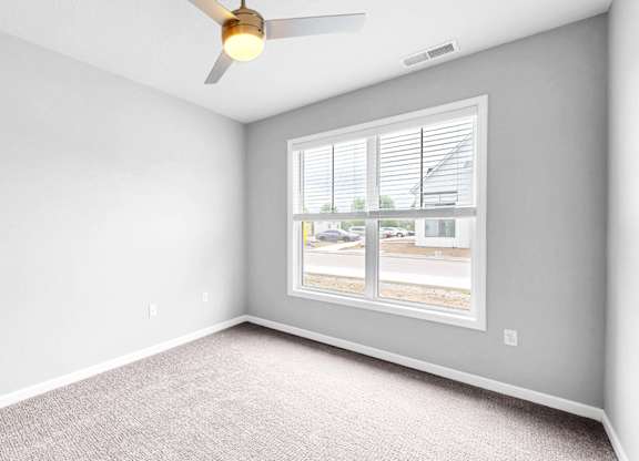 A room with a window showing a view of a street with cars and houses.