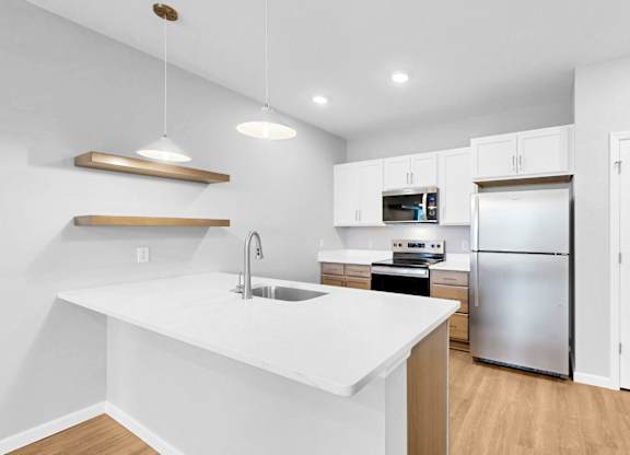 A modern kitchen with white countertops and stainless steel appliances.
