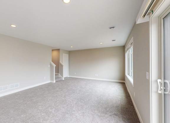 Empty carpeted room with sliding door access at Wildwood Lakeville Apartments, Lakeville, Minnesota