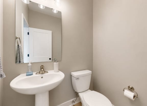 Powder room with pedestal sink and mirror at Wildwood Lakeville Apartments, Minnesota