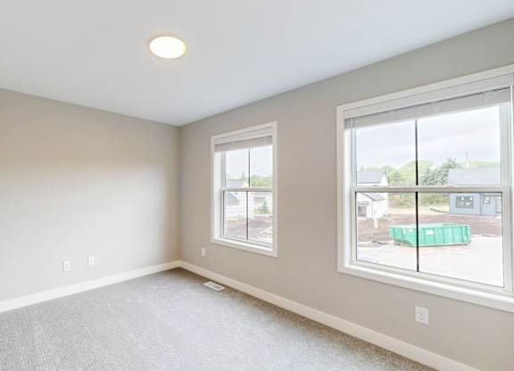 Empty carpeted bedroom with dual windows at Wildwood Lakeville Apartments, Minnesota, 55044
