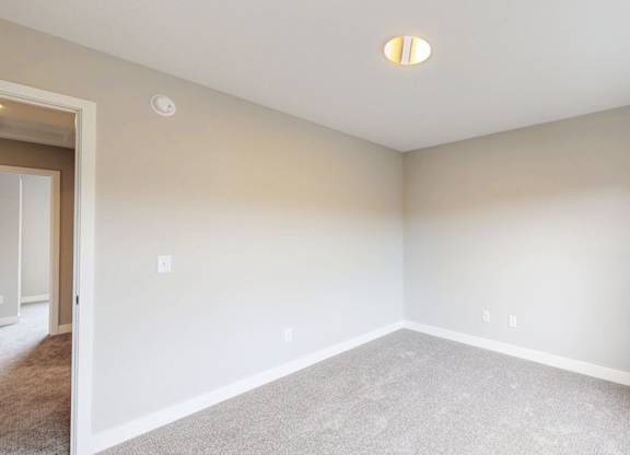 Empty carpeted room with vaulted ceiling at Wildwood Lakeville Apartments, Lakeville, Minnesota