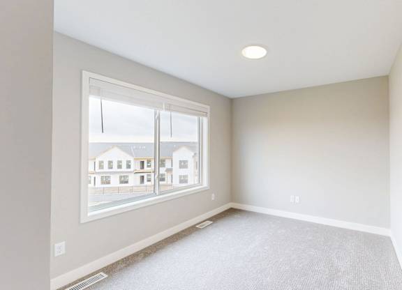 Empty carpeted room with window and recessed lighting at Wildwood Lakeville Apartments, Lakeville