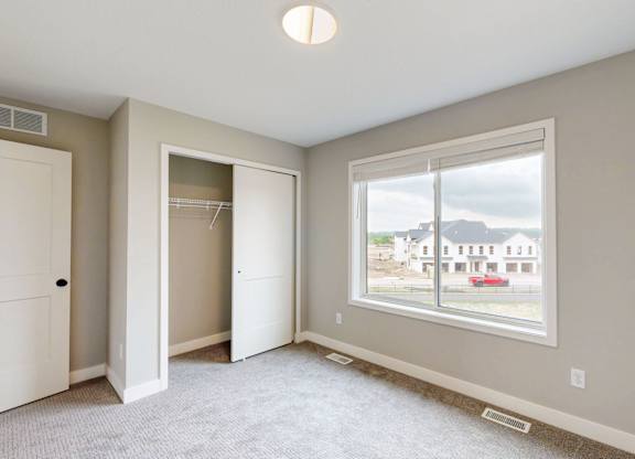 Bedroom with large window and open closet space at Wildwood Lakeville Apartments, Lakeville, 55044