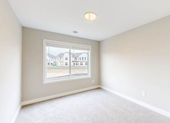 Empty carpeted room with window overlooking community at Wildwood Lakeville Apartments, Lakeville, MN 55044