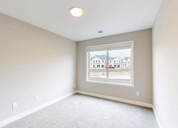 Empty carpeted room with large window at Wildwood Lakeville Apartments, Lakeville, MN