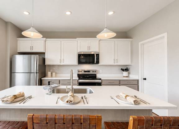Modern kitchen island with white countertops and seating at Wildwood Lakeville Apartments, Lakeville, Minnesota