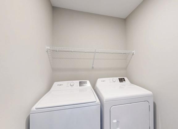 In unit washer and dryer with shelving above at Wildwood Lakeville Apartments, Lakeville, Minnesota