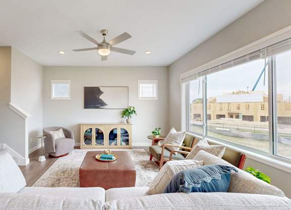 Living room with ceiling fan and large picture window at Wildwood Lakeville Apartments, Lakeville, MN