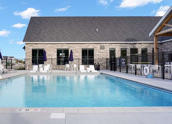 A swimming pool with a black fence and a building in the background.