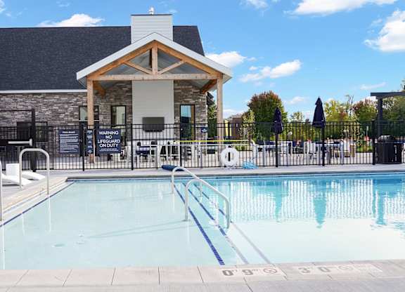 A swimming pool with a diving board and a building in the background.