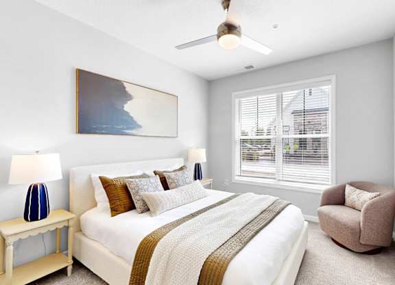 A bedroom with a large bed, a chair, and a painting on the wall.