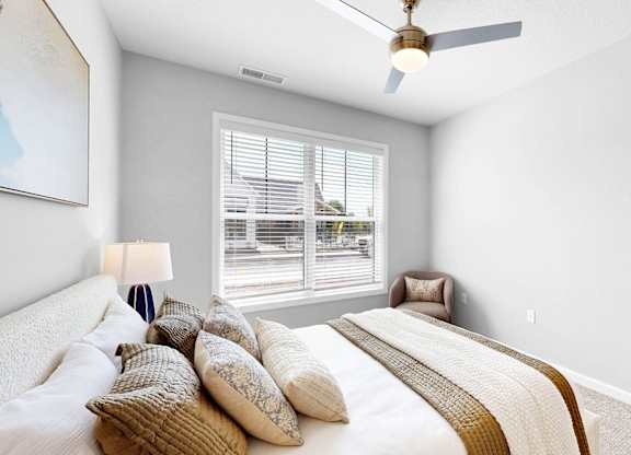 A bedroom with a large bed and a ceiling fan.