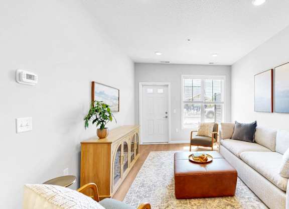 A living room with a white couch, a wooden cabinet, and a painting on the wall.