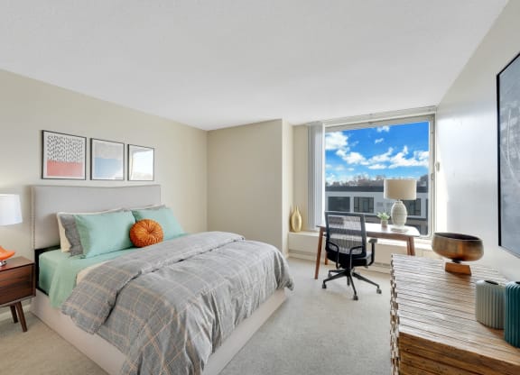 a bedroom with a bed and a desk with a window
