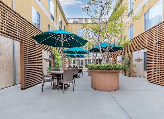 A Patio With Tables And Chairs And Umbrellas at Atrium Garden Apartment Homes, LLC, California