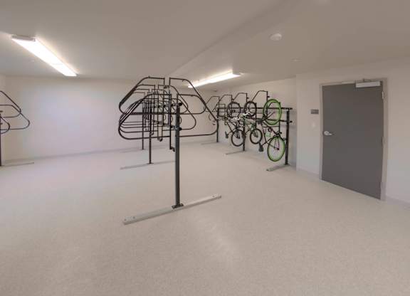 A room with a white floor and walls has a bicycle rack with several bicycles at Catalyst Mountain View, Mountain View, CA