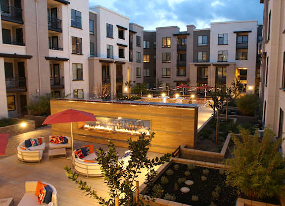 A patio with a table and chairs is surrounded by apartment buildings at Catalyst Mountain View, Mountain View, CA