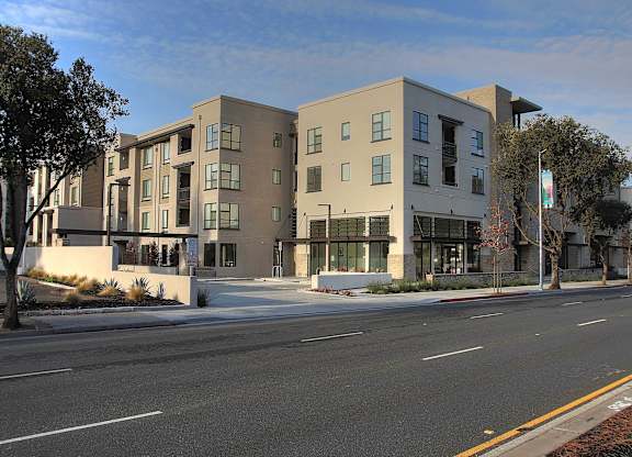 A modern apartment building with a parking lot in front at Catalyst Mountain View, Mountain View, CA