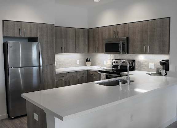 A modern kitchen with a stainless steel refrigerator and a white countertop at Catalyst Mountain View, Mountain View, CA