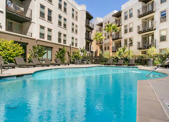A swimming pool in front of apartment buildings. at Cirrus Redwood City Apartments, Redwood City, CA, 94061